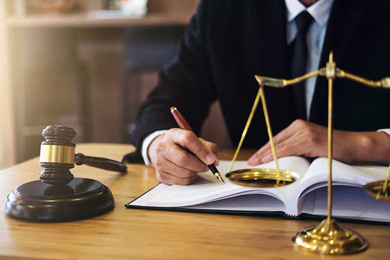 lawyer writing notes in front of a gavel